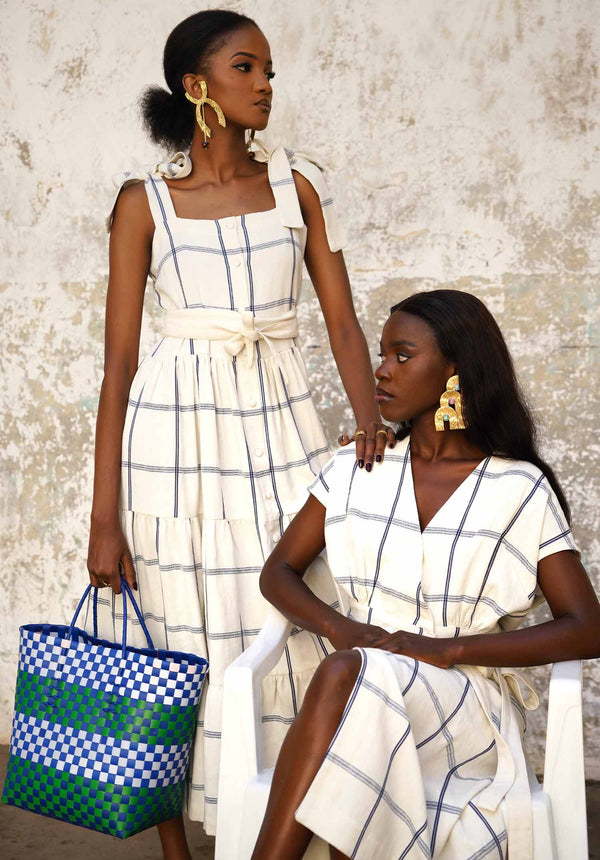 Two women wearing matching moyo wrap skirts with a textured wall background